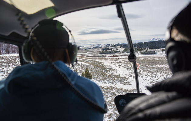 A lineman and pilot in a helicopter looking at a powerline
